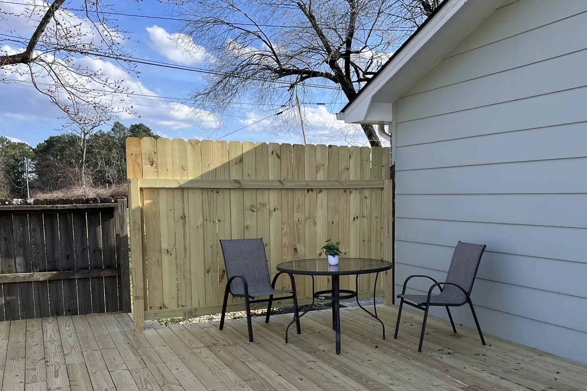An inviting exterior patio area featuring a table and chairs, a potted plant, and a wooden fence. The space feels relaxed and is ideal for morning coffee, afternoon reading, or casual family conversations after a day out.