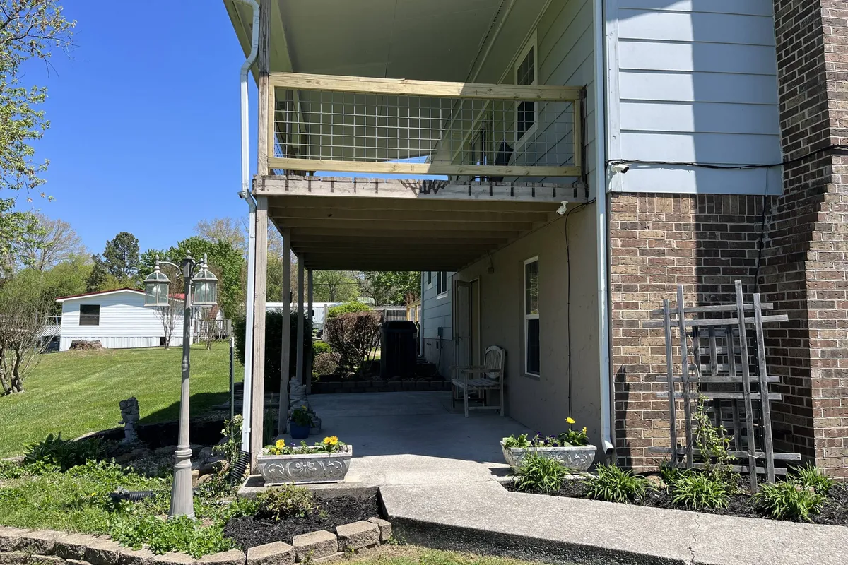 A welcoming exterior space featuring a covered patio with ample seating, a garden area, and a decorative lamp post. The scene suggests an inviting spot for relaxing outdoors, entertaining guests, or enjoying time with pets and family.