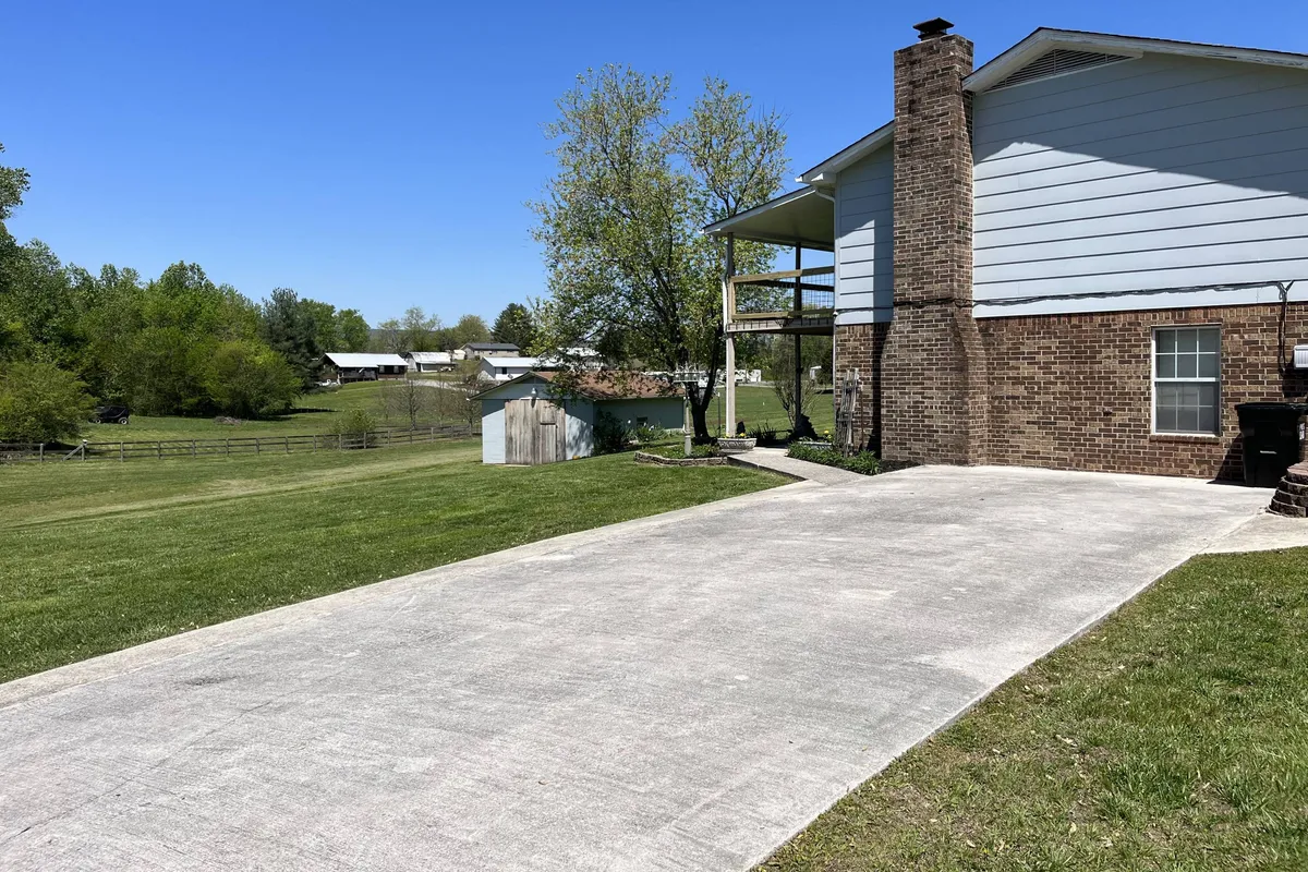 An exterior shot of the house and its multi-vehicle driveway, with grass and trees surrounding the property. There’s plenty of space visible for cars, boats, and trailers, while the peaceful setting hints at the home’s proximity to outdoor adventures.