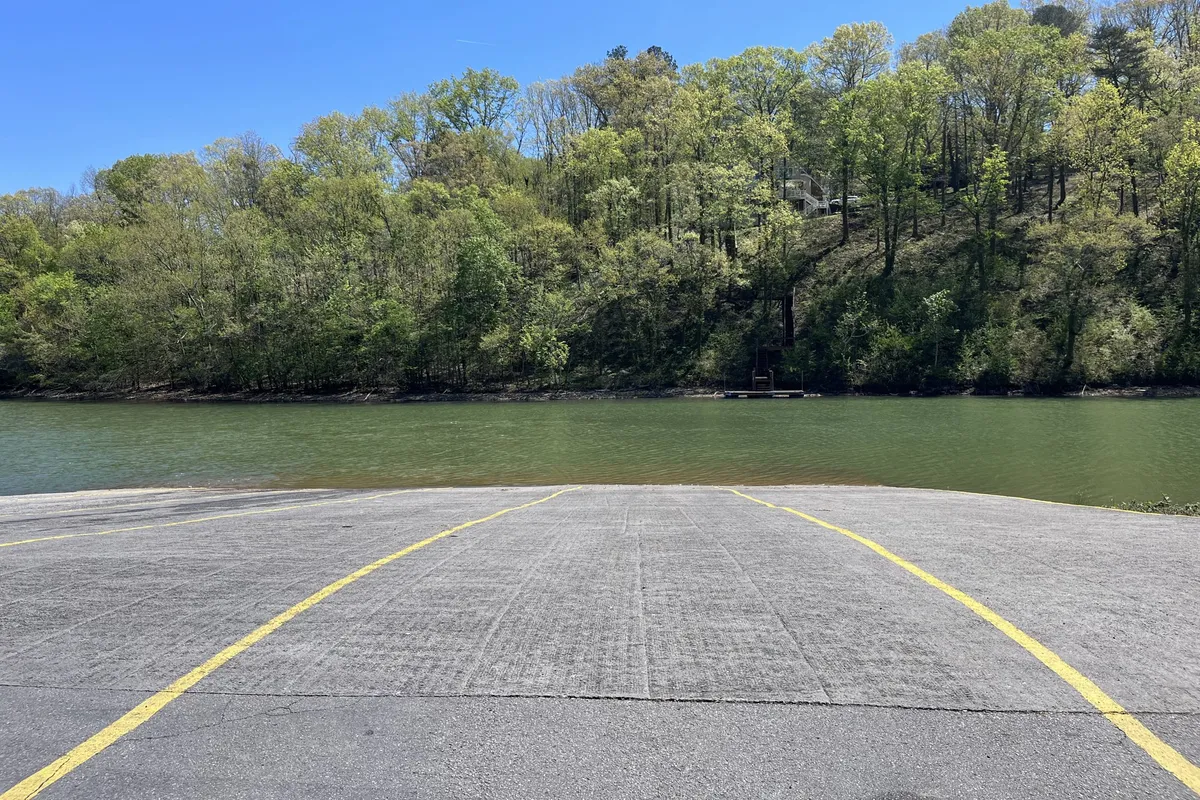 A peaceful exterior scene featuring calm water, lush greenery, and a boat ramp, offering another perspective of outdoor recreation options. The inviting landscape hints at possibilities for picnicking, wildlife spotting, or unwinding after a day of play.