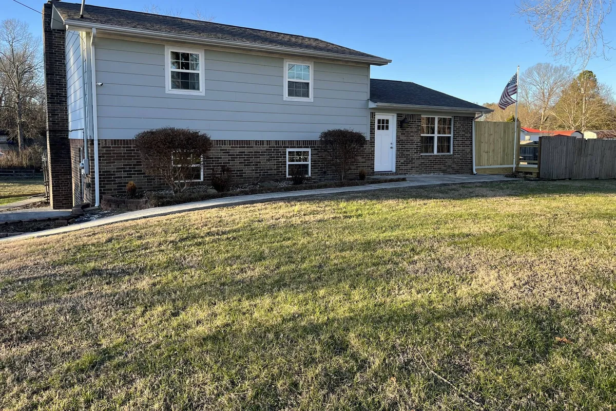 A welcoming view of the home’s front door, windows, and landscaped yard with an American flag. The scene suggests a friendly entrance for groups returning from the lake, and the yard space hints at pet-friendly amenities.